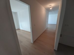 Slika hodnika v stanovanju brez pohištva, ki vodi v različne sobe.